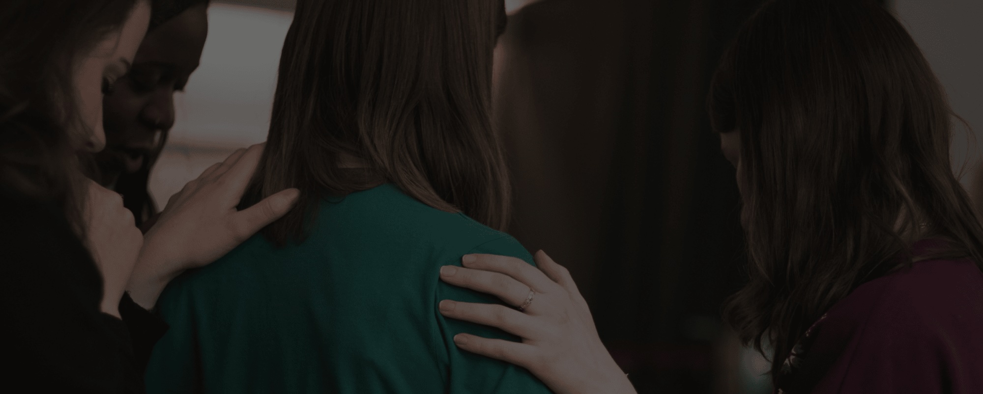 A group of women laying hands on someone and praying for them in unity. The source is from Unsplash.com.